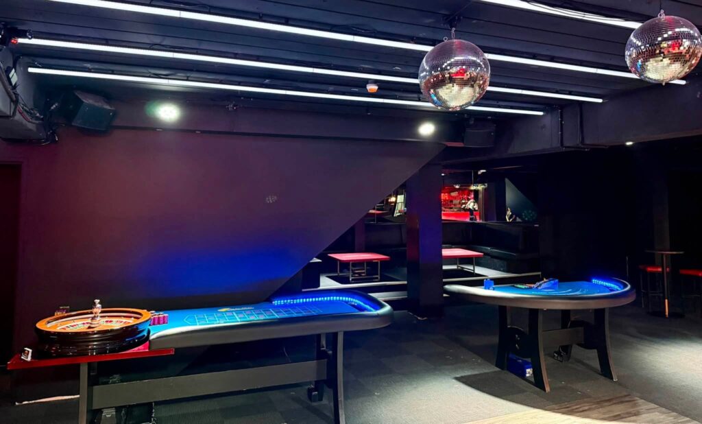 Casino Roulette and Blackjack tables beneath disco balls at The Milton Rooftop & Sports Bar